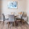 a dining table with chairs and a painting on the wall