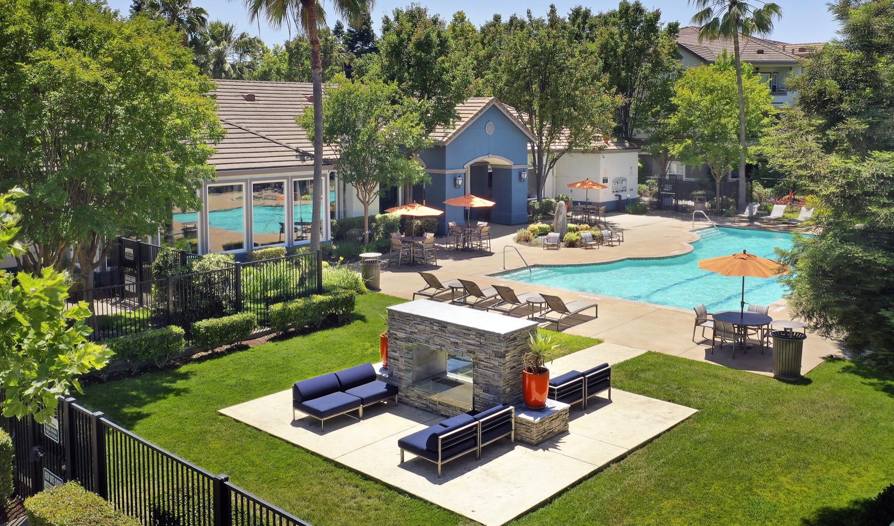 a building with a pool and trees and lounge area