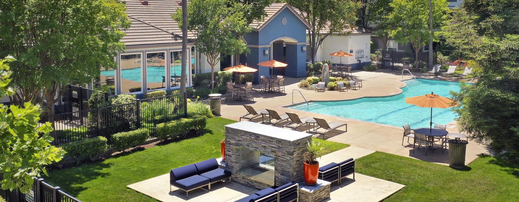 a building with a pool and trees and lounge area